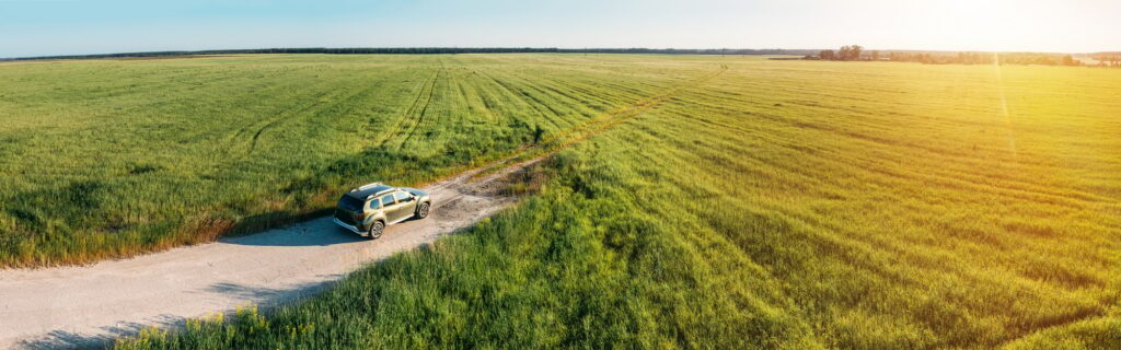 Aerial view of Renault Duster car SUV parked near countryside road in field rural landscape. Aerial