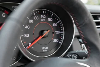 Tableau de bord d'une voiture avec le compteur de vitesse indiquant 180 mph et l'échelle en km/h visible