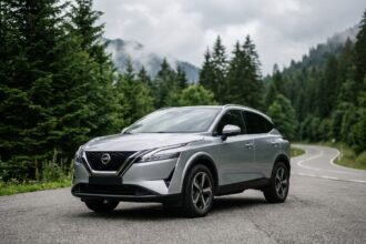 Nissan Qashqai argent garé sur une route de montagne entourée de forêts de pins, vue 3/4 avant mettant en valeur son design aérodynamique et sa garde au sol surélevée