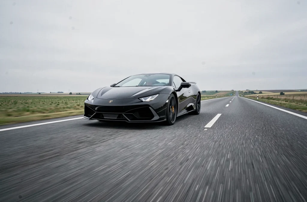 Voiture de sport noire sur autoroute illustrant la vitesse de 180 mph soit environ 290 km/h